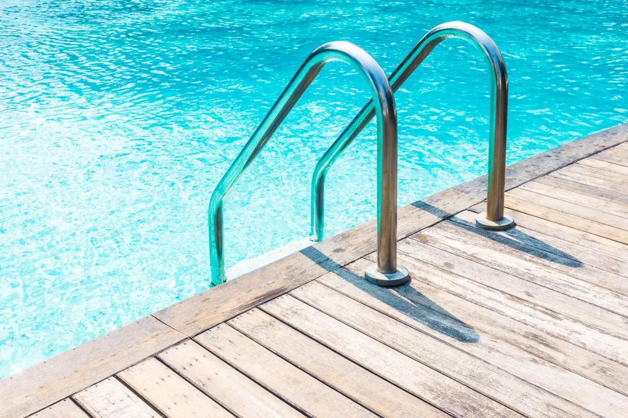 Escaleras de piscina de acero inoxidable sobre cubierta de madera. ¿Cuánto cuesta hacer una piscina?