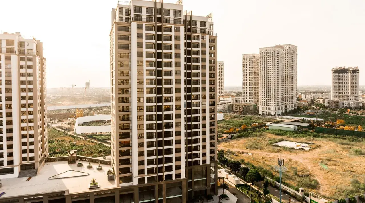 Edificios modernos se alzan sobre un **terreno urbano no consolidado**, con vegetación y construcciones en proceso.