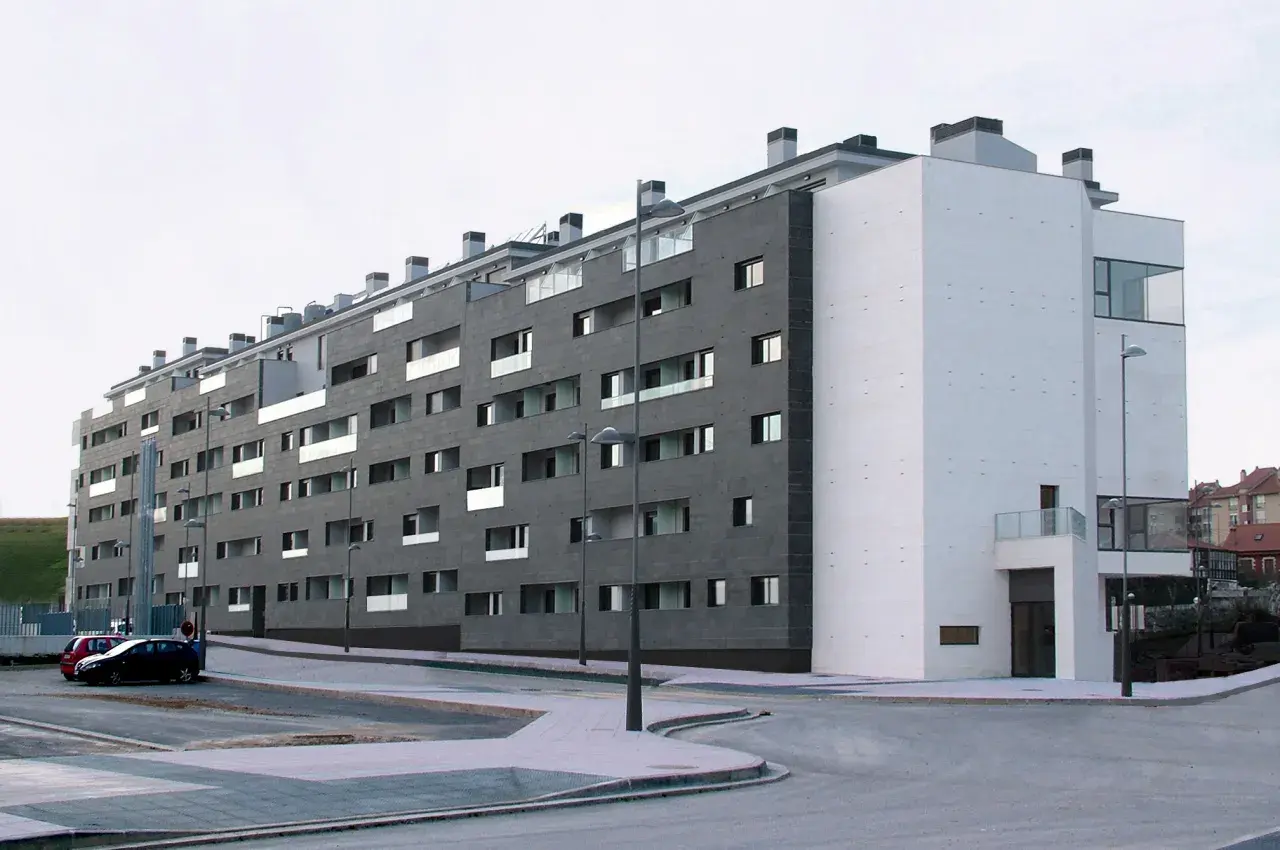 Edificio moderno con fachada de piedra oscura y blanca. ¿Buscas como saber si una vivienda es VPO? Este edificio podría serlo.