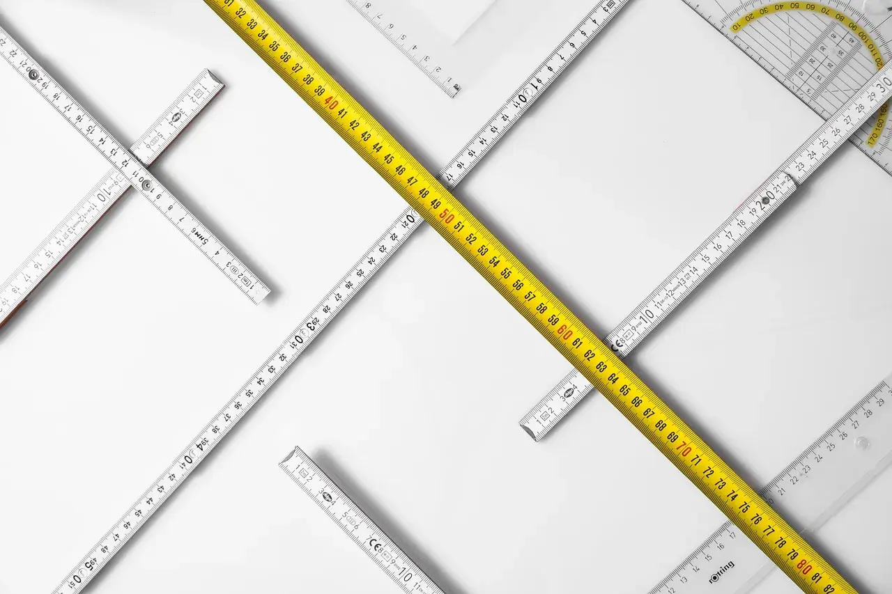 Reglas de medición de diferentes tipos, incluyendo una cinta métrica amarilla, dispuestas en un patrón que sugiere la búsqueda de un cuerpo cierto.