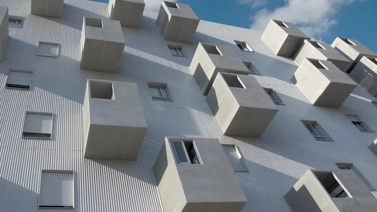 Edificio moderno con balcones cúbicos que parecen flotar, como si fueran parte de una socimi innovadora.