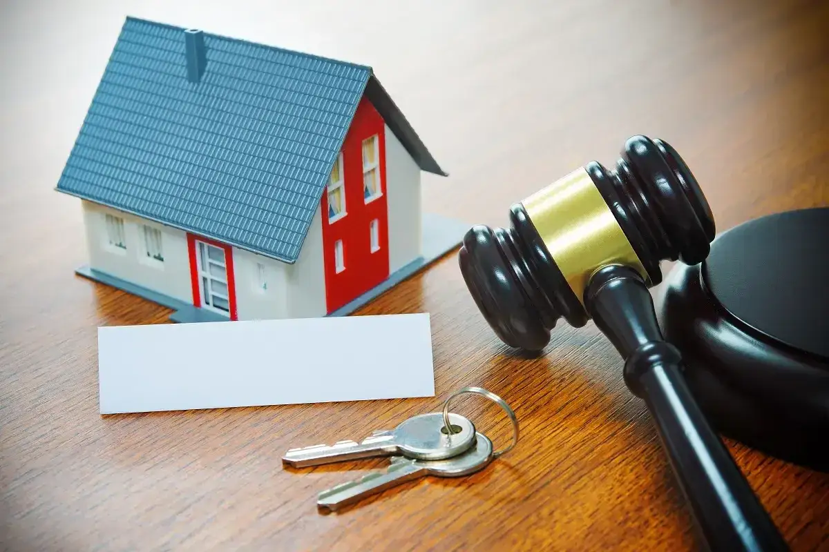 Maqueta de casa, llaves y mazo de juez. Un ejemplo de derecho de retracto en una subasta inmobiliaria.