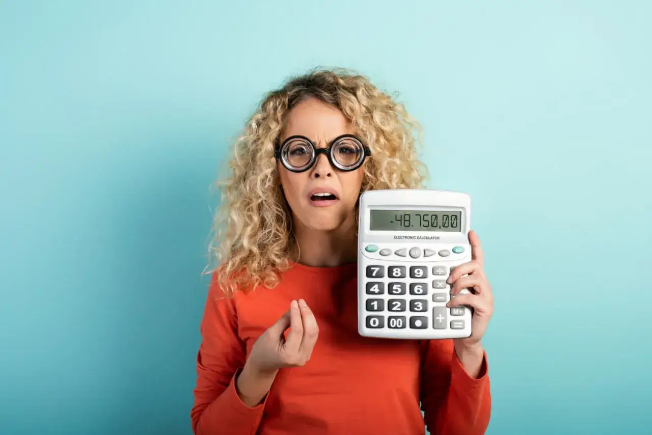 Mujer con rulos y gafas grandes muestra calculadora con 