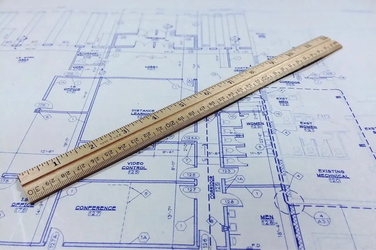 Regla de madera sobre planos arquitectónicos. El precio del informe pericial de arquitecto se calcula con precisión.