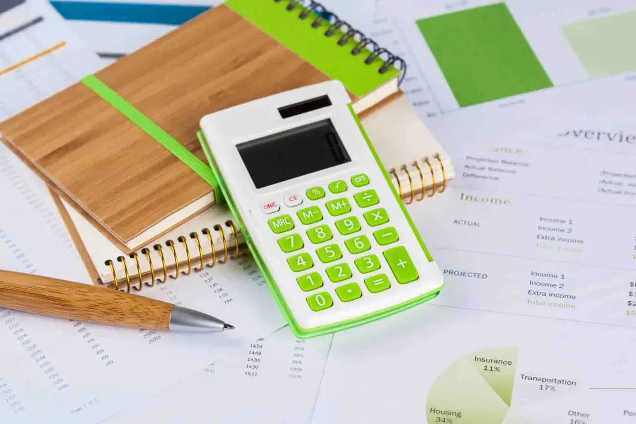 Calculadora y cuaderno sobre documentos financieros. Planificando cómo refinanciar hipoteca para optimizar gastos.