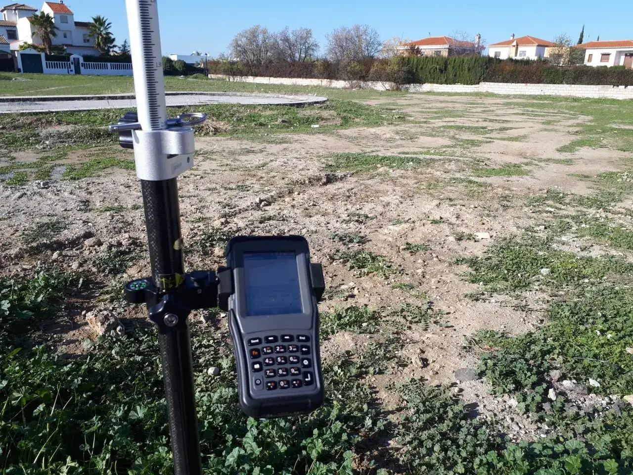 Equipo topográfico en terreno baldío, listo para realizar un deslinde que es la delimitación de una propiedad.