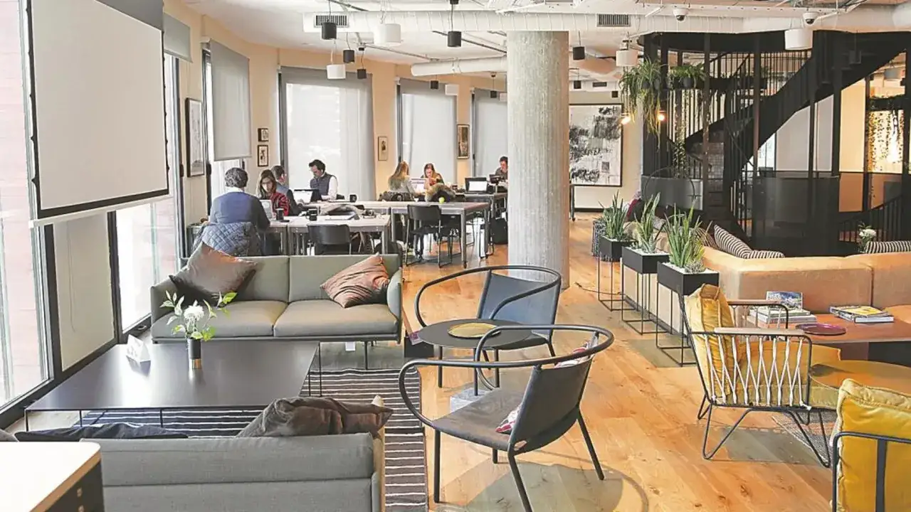 Espacio moderno de coliving que es, con áreas de trabajo, descanso y una escalera de caracol.