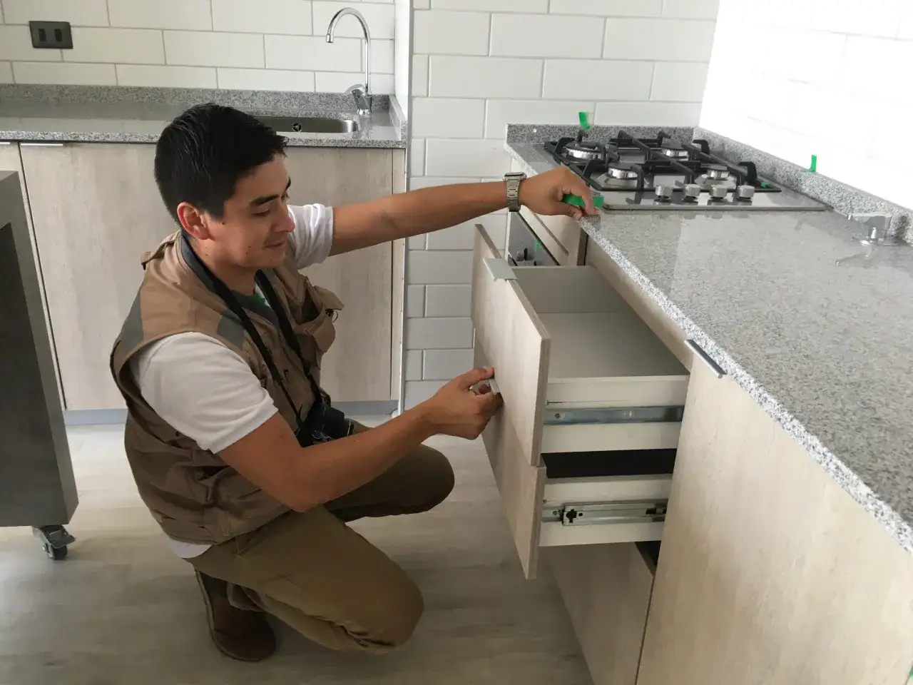 Inspección de cocina para alquiler de casa. Un hombre revisa cajones y encimera.