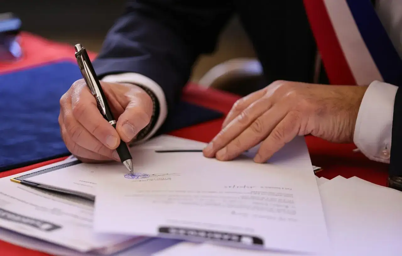 Persona firma un documento oficial, quiz&aacute;s consultando cu&aacute;nto cuesta un tasador de herencias para un proceso legal.