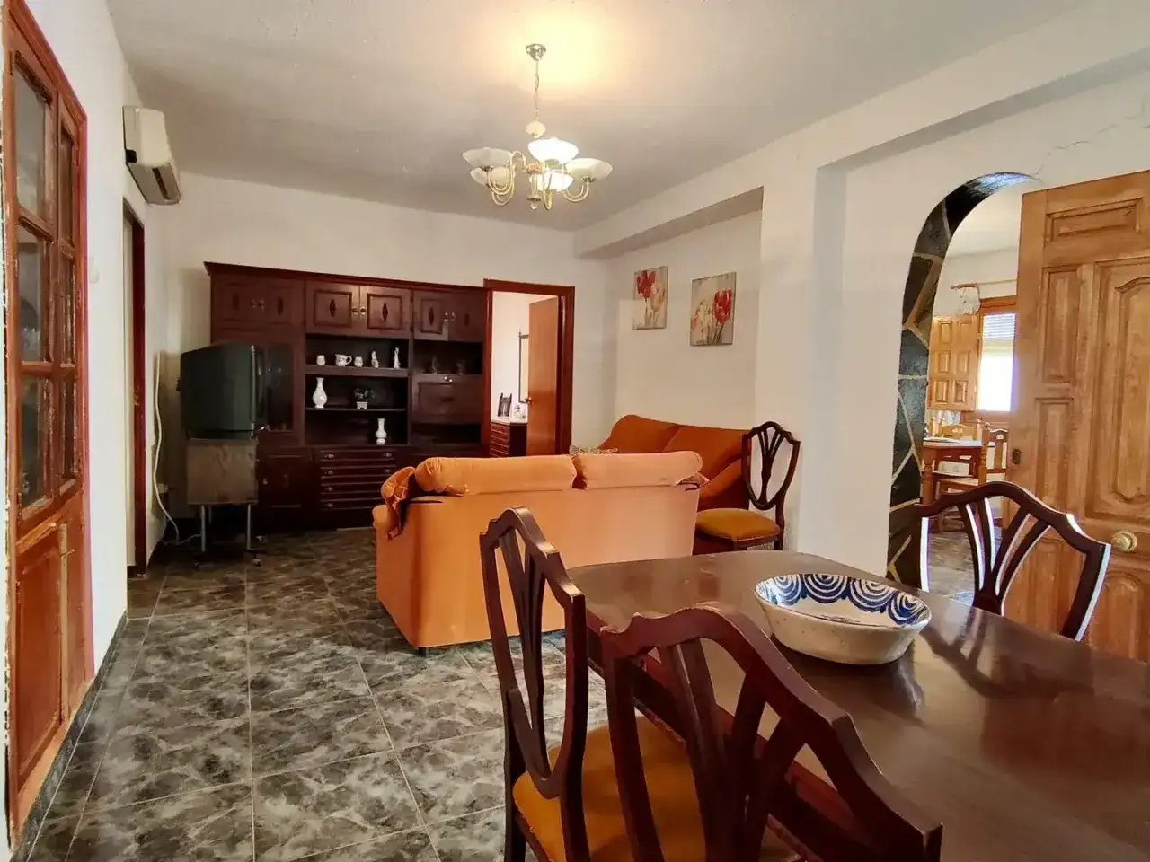 Salón con muebles de madera oscura, sofás naranjas y mesa de comedor. Las gradual homes opiniones sobre este espacio sugieren un ambiente acogedor.