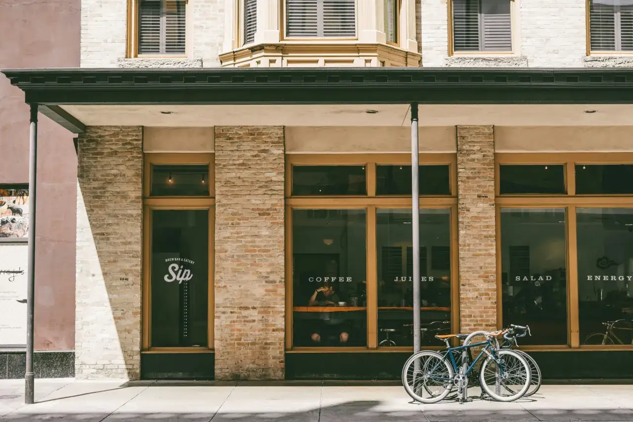 Fachada de local comercial con bicicletas aparcadas. La fachada de ladrillo y cristal muestra 